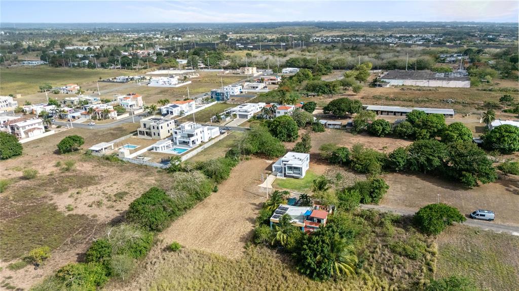 An aerial view shows several modern houses surrounded by open land and scattered trees — PR 459 KM13.3 Bo. Bejucos INT CALLE LAS UVAS, ISABELA, PR