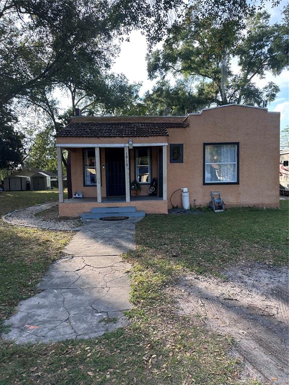 A single-story stucco house with a covered front porch and a cracked concrete walkway — 1910 WILLIAM CLARK AVENUE, SANFORD, FL