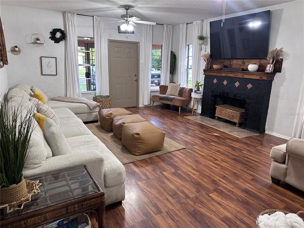 A living room features a large sectional sofa, leather ottomans, and a black brick fireplace — 1910 WILLIAM CLARK AVENUE, SANFORD, FL