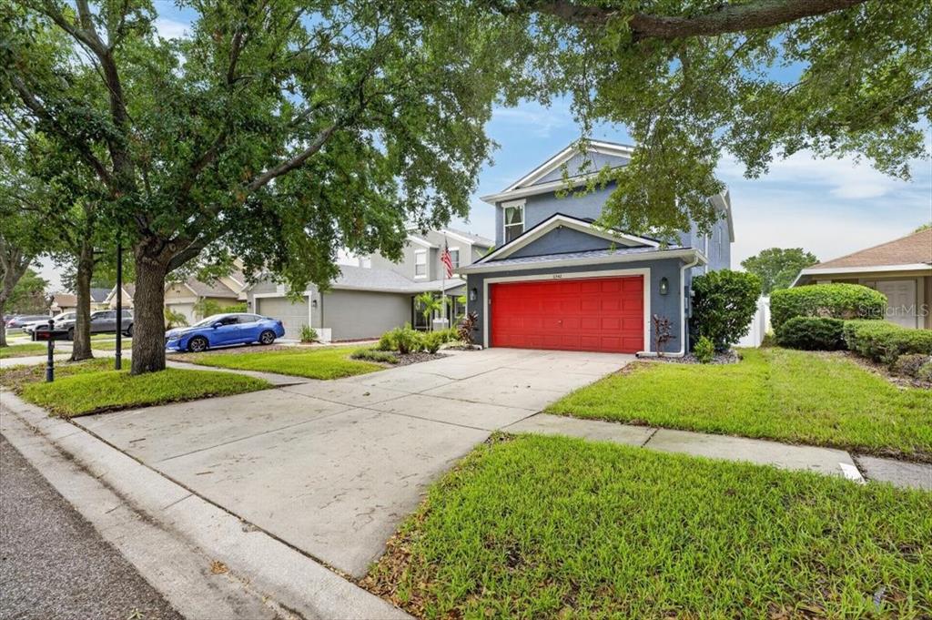 A two-story blue house with a bright red garage door and a concrete driveway — 11342 COCOA BEACH DRIVE, RIVERVIEW, FL