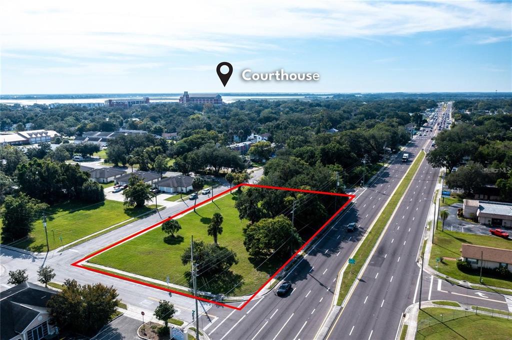 An aerial view shows a vacant, grass-covered lot outlined in red next to a highway — 0 JOHN YOUNG PARKWAY, KISSIMMEE, FL