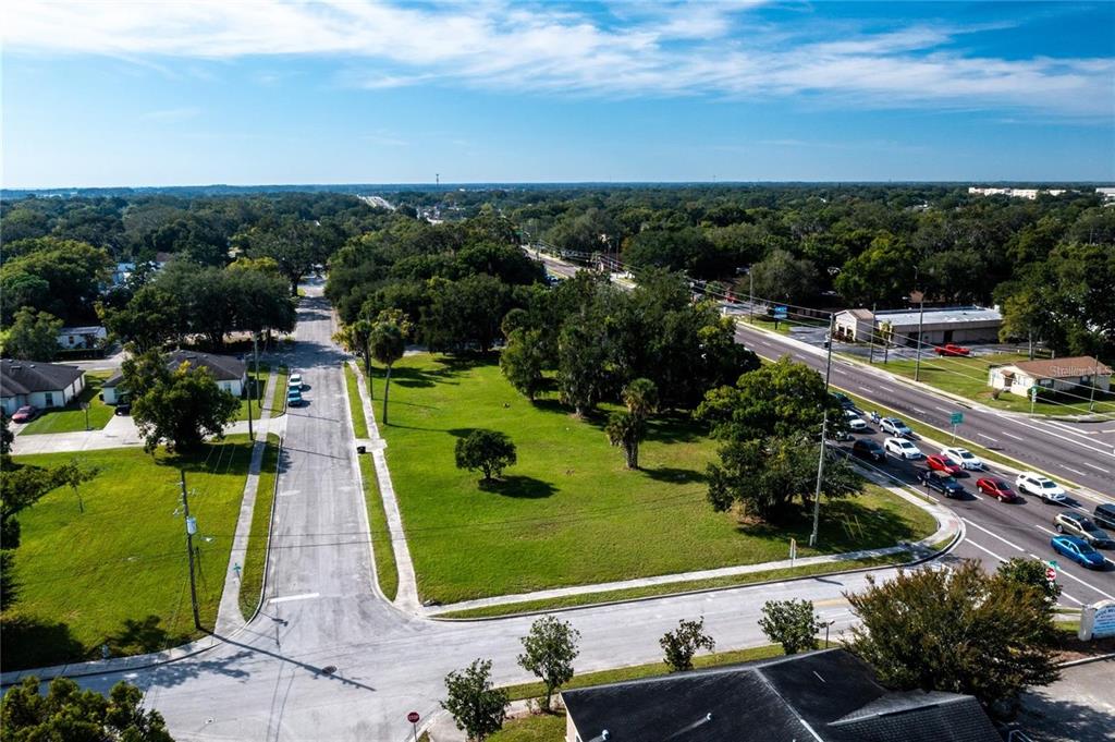 An aerial view shows a vacant grassy lot situated between a residential street and a highway — 0 JOHN YOUNG PARKWAY, KISSIMMEE, FL