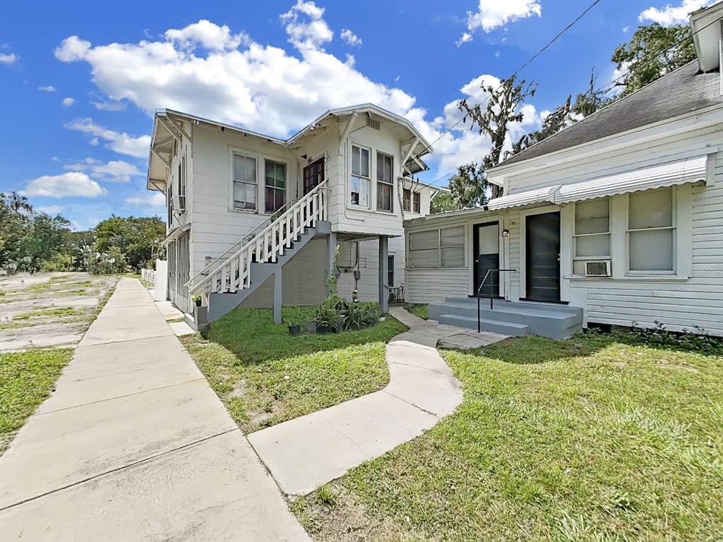 An exterior view of a two-story white house with an outdoor staircase and concrete walkway — 601 W BAKER STREET, PLANT CITY, FL