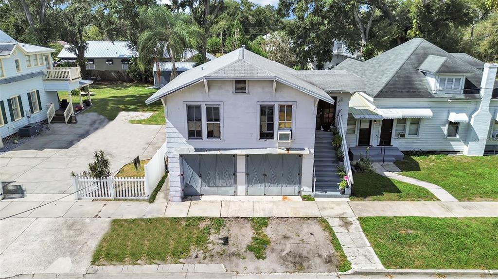 An exterior view of a two-story building with a ground-level garage and upper-level living space — 601 W BAKER STREET, PLANT CITY, FL