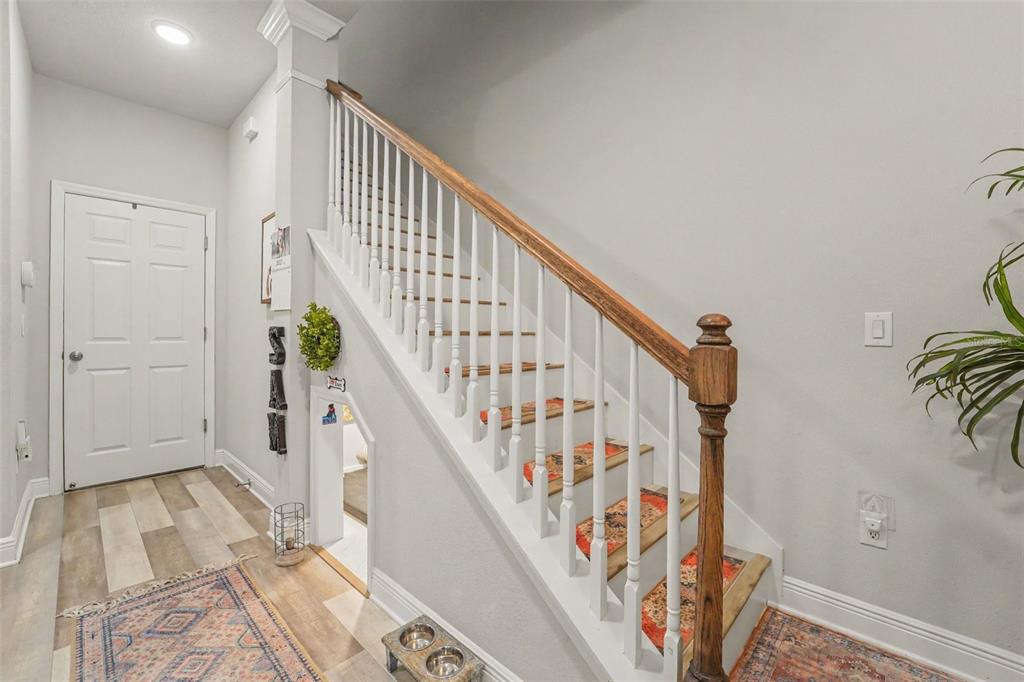 An entryway features a staircase with white railings, a wooden handrail, and a small pet nook — 9567 CAVENDISH DRIVE, TAMPA, FL