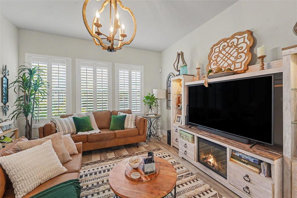 A living room features leather sofas, a fireplace media console, and a wooden chandelier — 9567 CAVENDISH DRIVE, TAMPA, FL