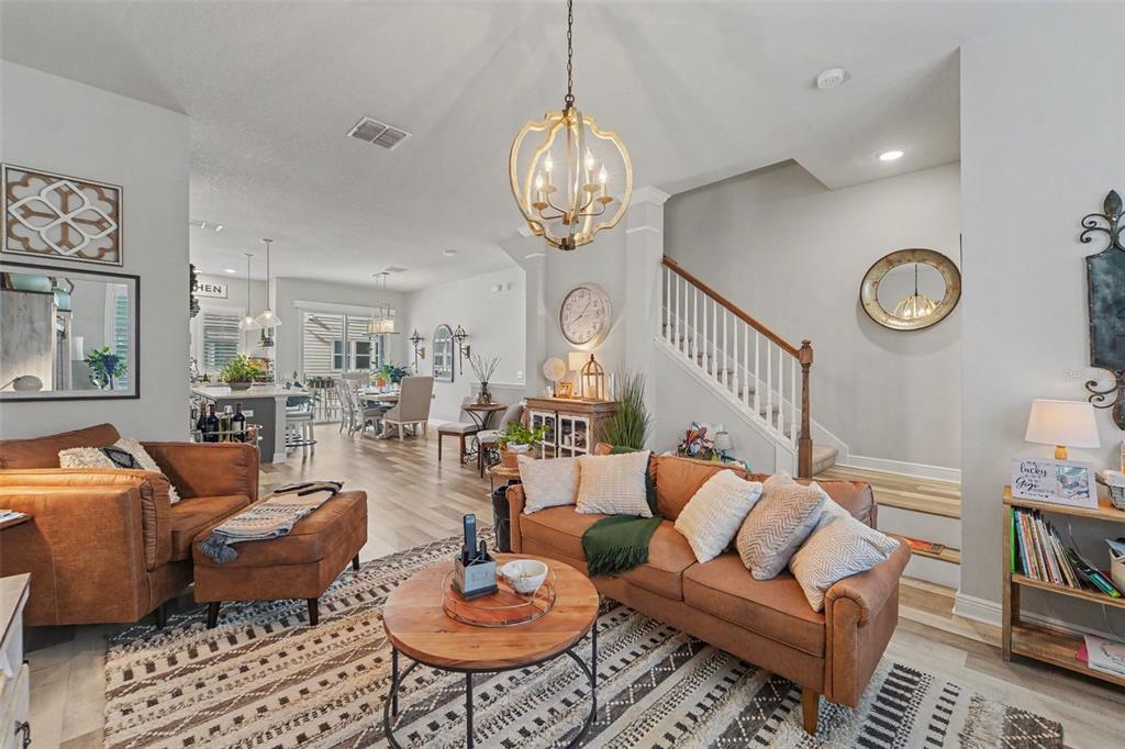 A living room with leather furniture, a patterned rug, and a staircase leads to a kitchen — 9567 CAVENDISH DRIVE, TAMPA, FL