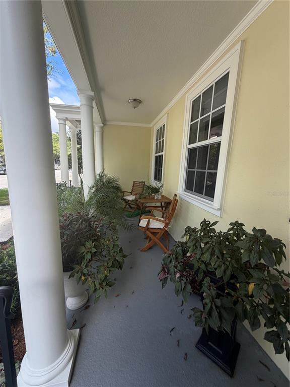 A covered porch features white columns, yellow walls, potted plants, and wooden patio furniture — 1425 CHATFIELD PLACE, ORLANDO, FL