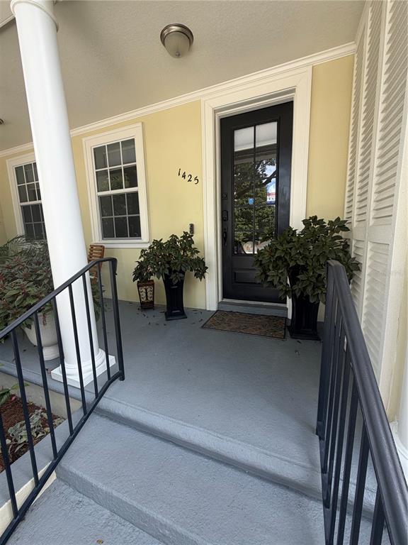 A front porch features a black door, a white column, and potted plants — 1425 CHATFIELD PLACE, ORLANDO, FL
