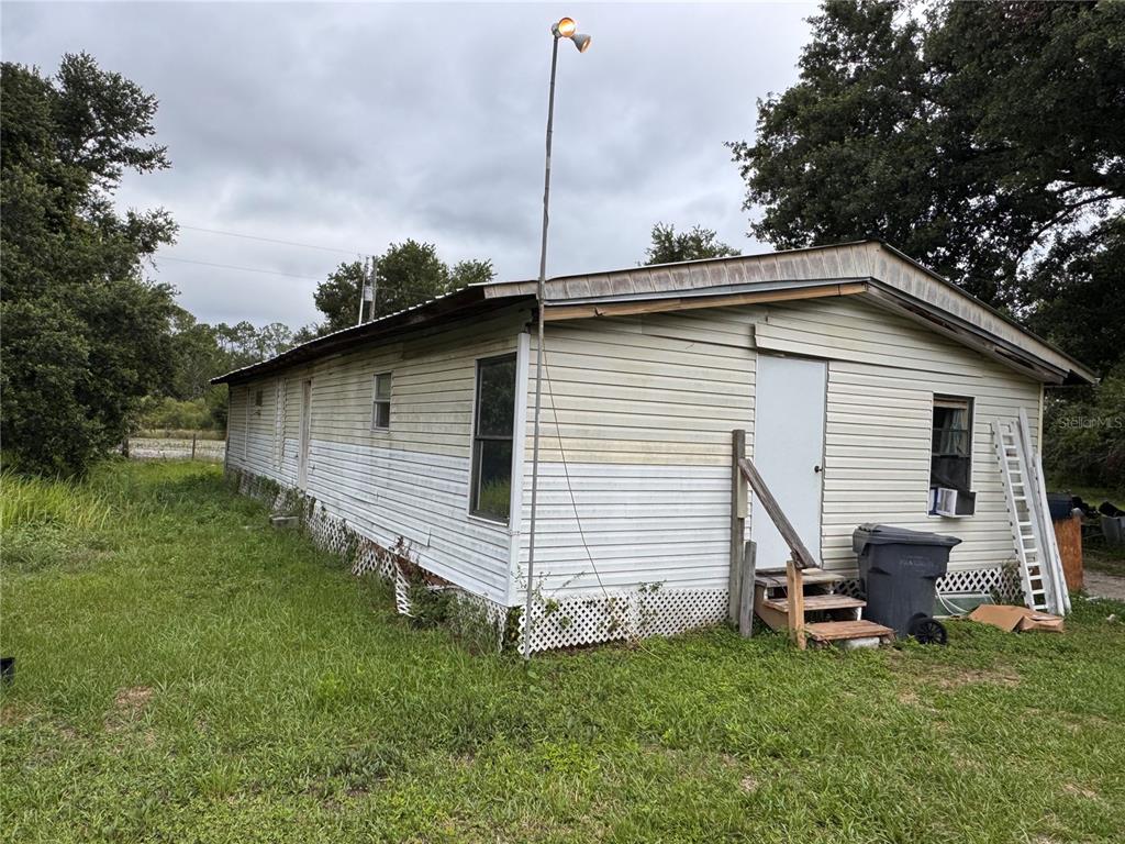 An exterior view of a single-wide mobile home with light siding and a metal roof — 12315 RANCHLAND TRAIL, LAKELAND, FL