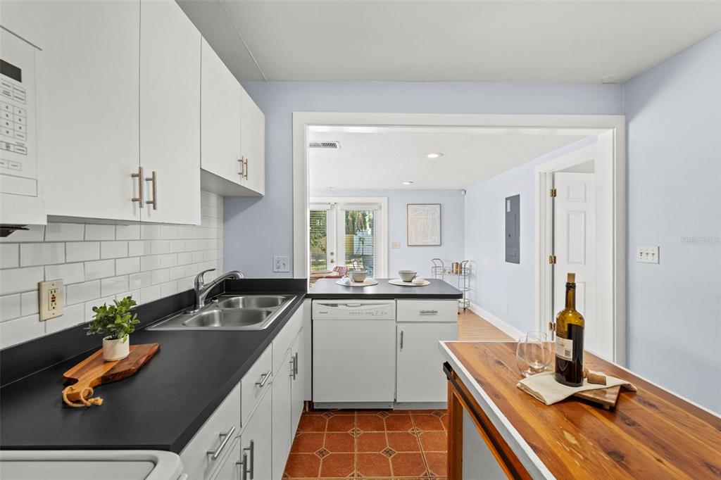 A kitchen with white cabinets, black countertops, a subway tile backsplash, and a wooden island — 3313 PRICE AVENUE, TAMPA, FL