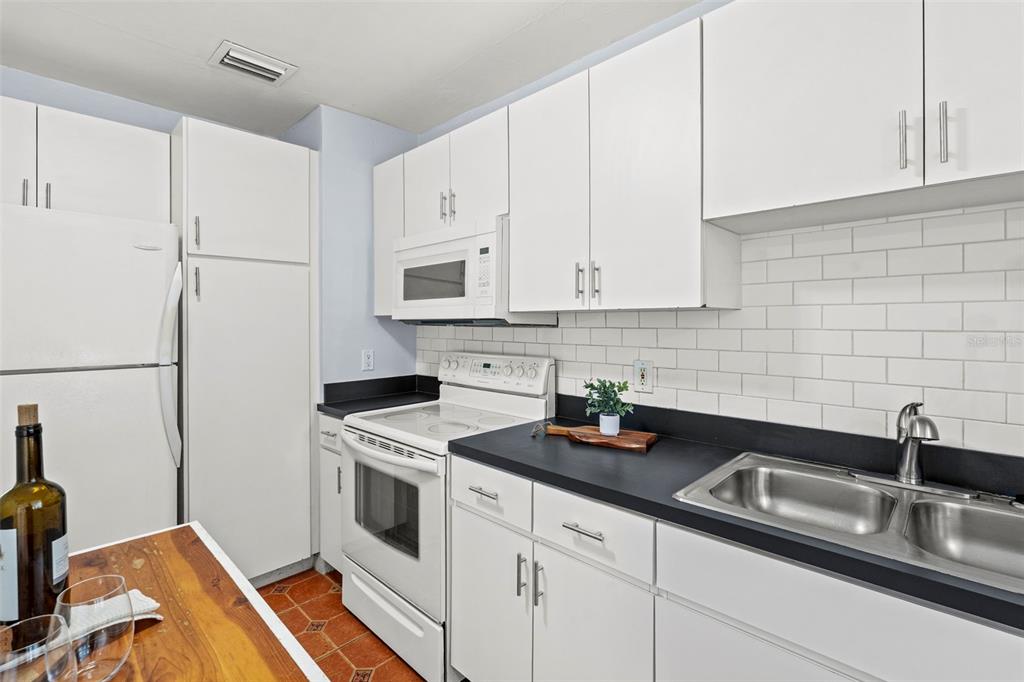 A kitchen with white cabinets, black countertops, a white stove, and a white refrigerator — 3313 PRICE AVENUE, TAMPA, FL