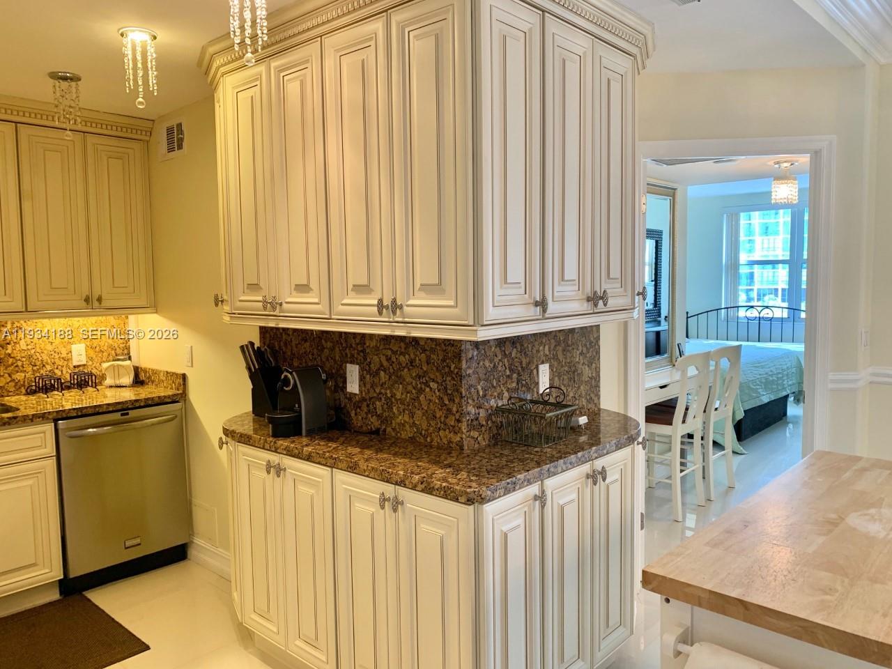 A kitchen features cream-colored cabinets, granite countertops, and a stainless steel dishwasher — 1985 S Ocean Dr # 3C, Hallandale Beach FL 33009, HALLANDALE BEACH, FL