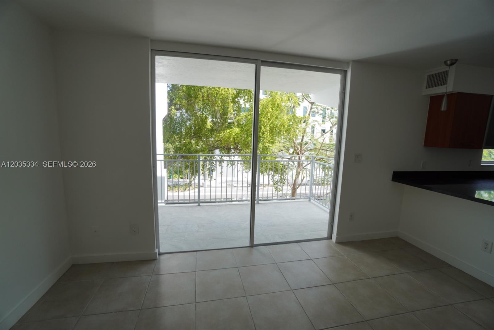 A room with tiled floors features a sliding glass door leading to a balcony — 680 NE 64th St # A302, Miami FL 33138, MIAMI, FL