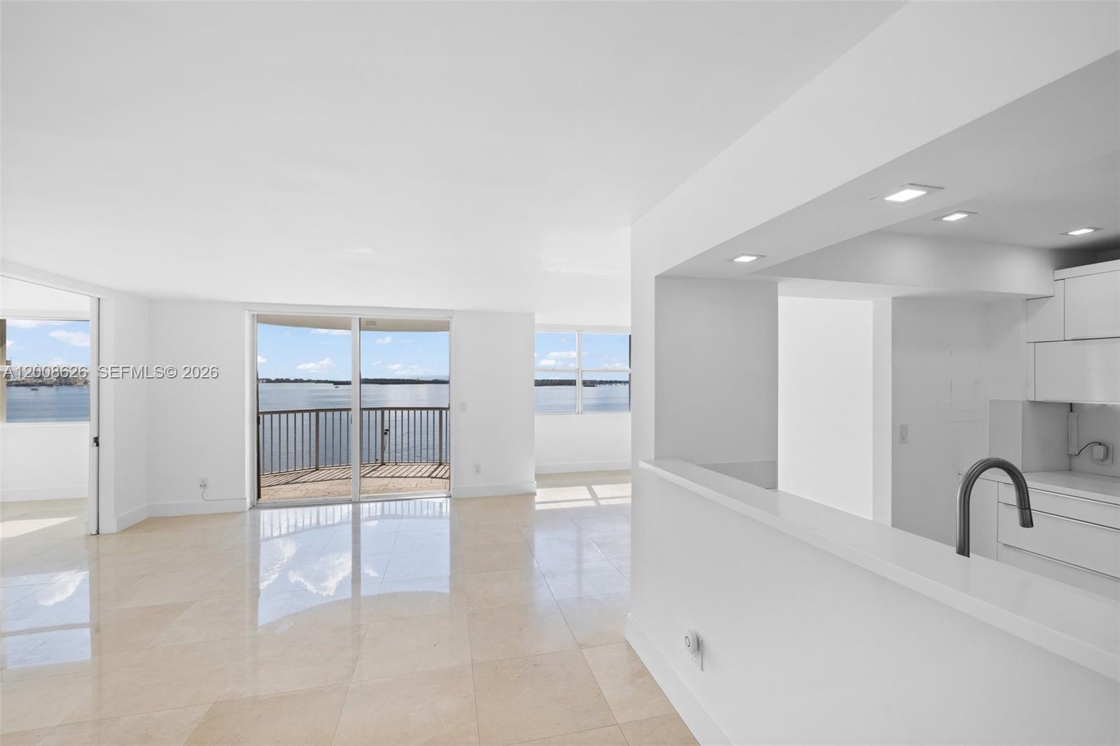 An open-concept living area features white walls, tile flooring, and a view of the water — 1420 Brickell Bay Dr # 1001A, Miami FL 33131, MIAMI, FL