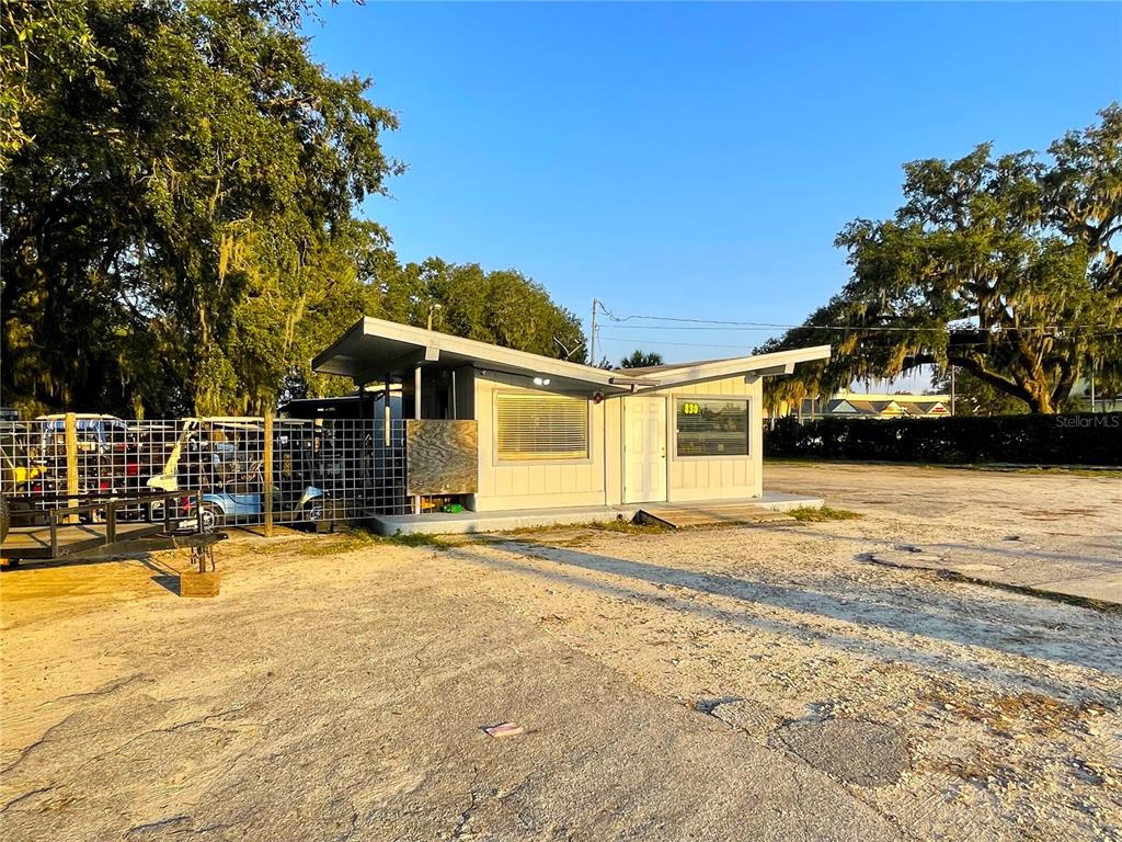 A small, light-colored commercial building with a flat, angled roof sits on a gravel lot — 830 S MAIN STREET, WILDWOOD, FL