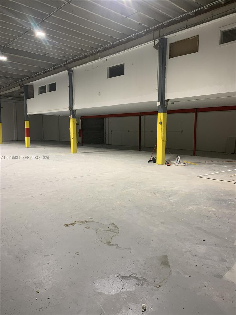 This industrial warehouse space features a concrete floor, yellow support columns, and a mezzanine level — HOMESTEAD, FL