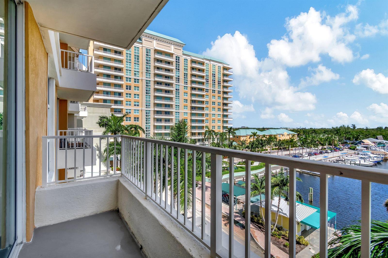 A balcony view overlooking a marina, palm trees, and a large multi-story residential building — 100 NE 6th Street # 505, Boynton Beach FL 33435, BOYNTON BEACH, FL