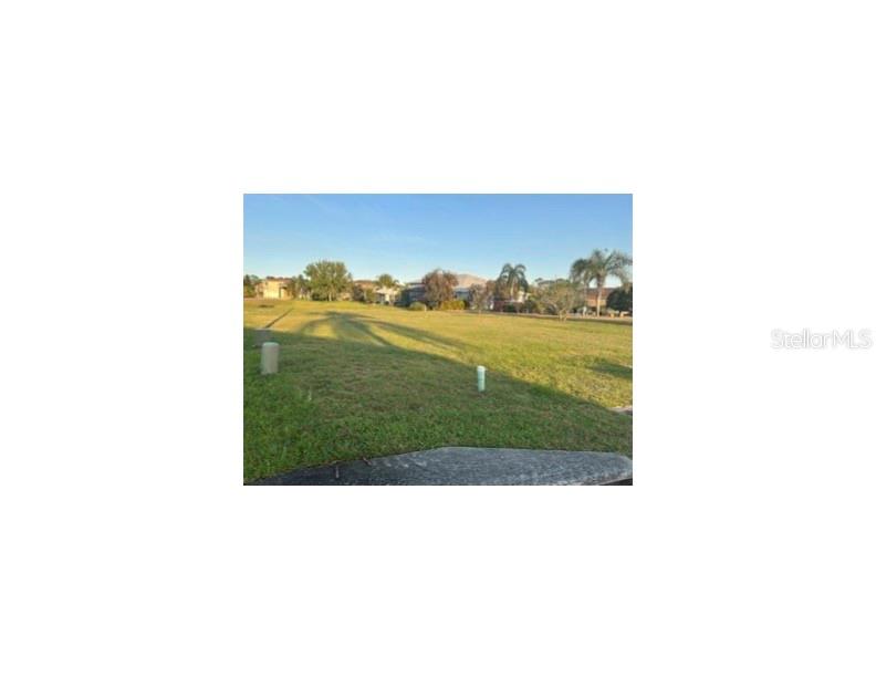 A vacant, grassy residential lot features two utility markers in the foreground under a blue sky — 440 NOLANE LANE, POLK CITY, FL