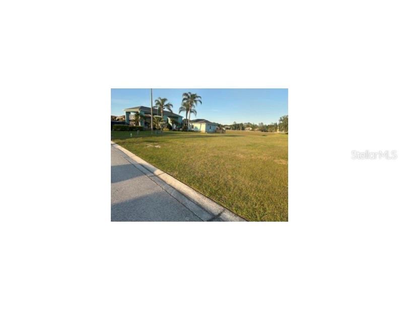 A vacant grassy lot sits next to a residential house under a clear blue sky — 440 NOLANE LANE, POLK CITY, FL