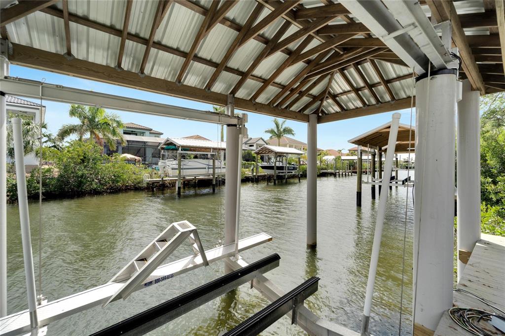 A covered boat lift structure sits over a canal with other boat docks in the background — 534 ESTUARY SHORE LANE, APOLLO BEACH, FL