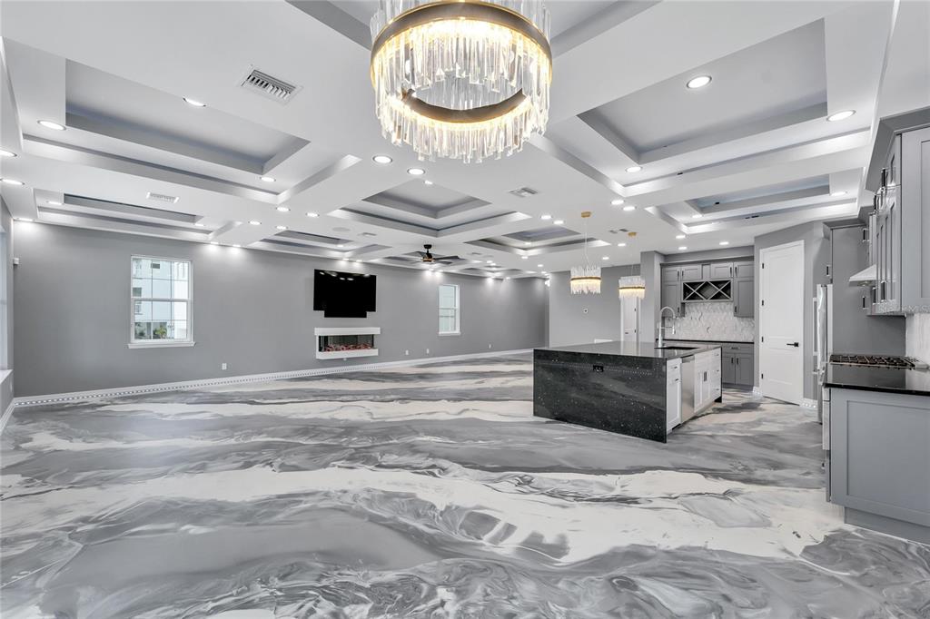 A spacious open-concept kitchen and living area features a marbled epoxy floor and coffered ceilings — 534 ESTUARY SHORE LANE, APOLLO BEACH, FL
