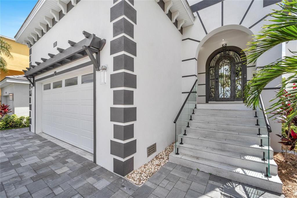 A white house exterior features a garage, a glass-railed staircase, and a decorative arched door — 534 ESTUARY SHORE LANE, APOLLO BEACH, FL