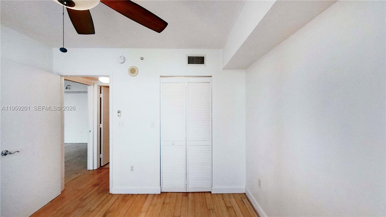 A room with white walls, hardwood floors, a ceiling fan, and a louvered closet door — 31 SE 5th St # 2408, Miami FL 33131, MIAMI, FL
