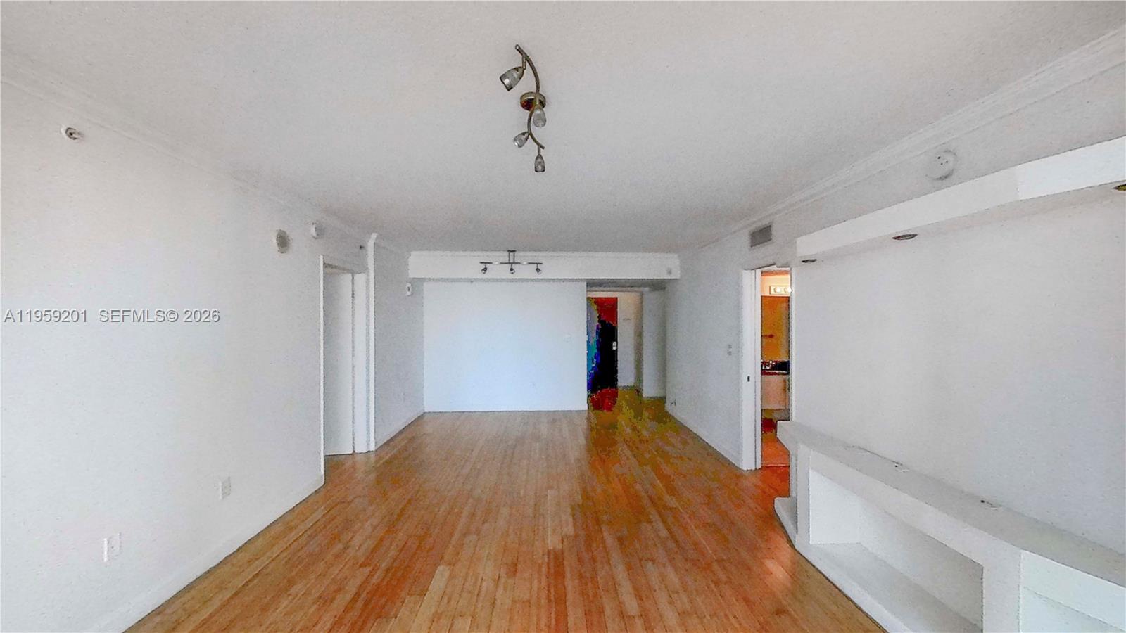 An empty living room features hardwood floors, white walls, and two modern ceiling light fixtures — 31 SE 5th St # 2408, Miami FL 33131, MIAMI, FL