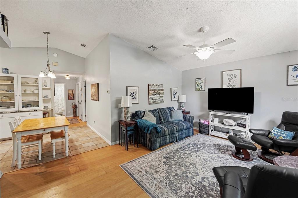 A living room with a striped sofa, television, and an adjacent dining area with tile floors — 1934 29TH AVENUE N, ST PETERSBURG, FL