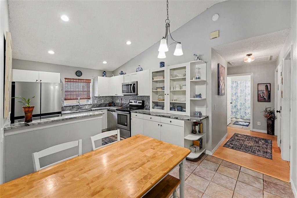 A kitchen with white cabinets, stainless steel appliances, and a wooden dining table — 1934 29TH AVENUE N, ST PETERSBURG, FL