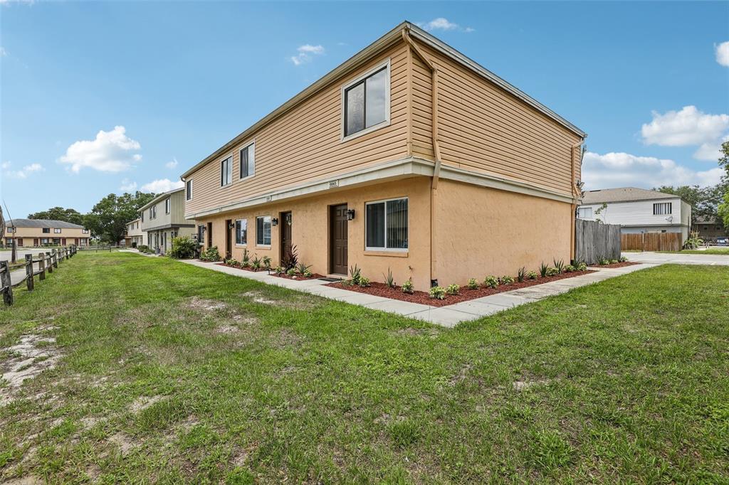 A two-story townhouse with tan siding and stucco exterior sits on a grassy lot — 12057 TIFT CIRCLE, ORLANDO, FL