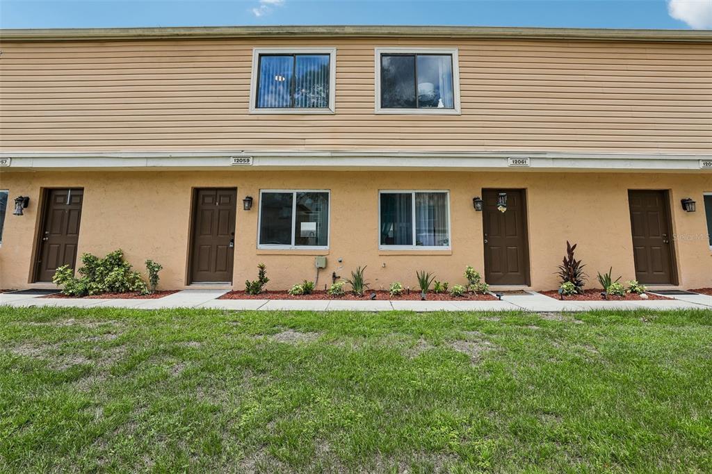 A two-story townhouse exterior with tan stucco, brown doors, and light brown horizontal siding — 12057 TIFT CIRCLE, ORLANDO, FL
