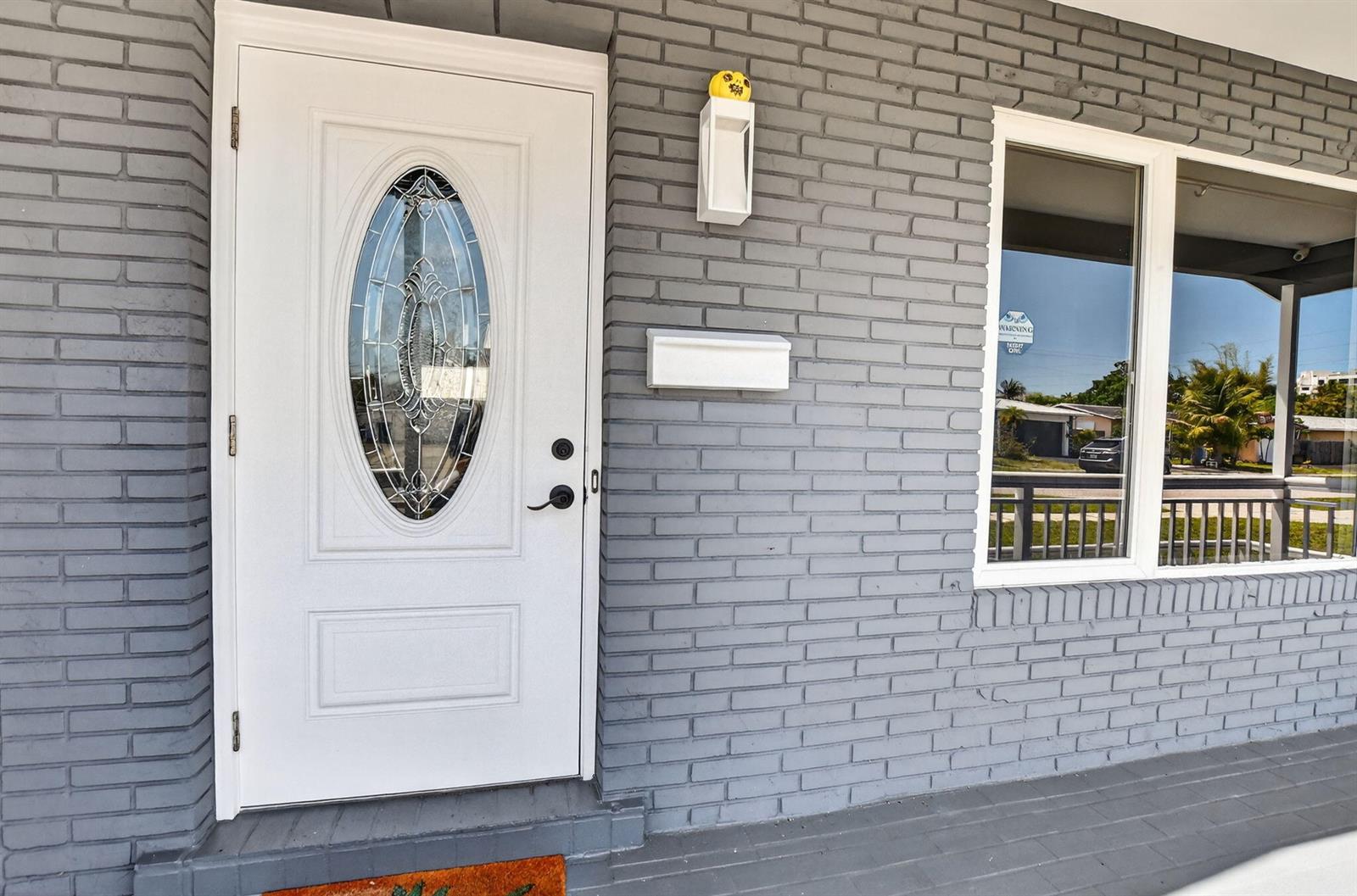 A white front door with an oval glass insert is set in a gray brick wall — 257 SW 5th Street, Boca Raton FL 33432, BOCA RATON, FL