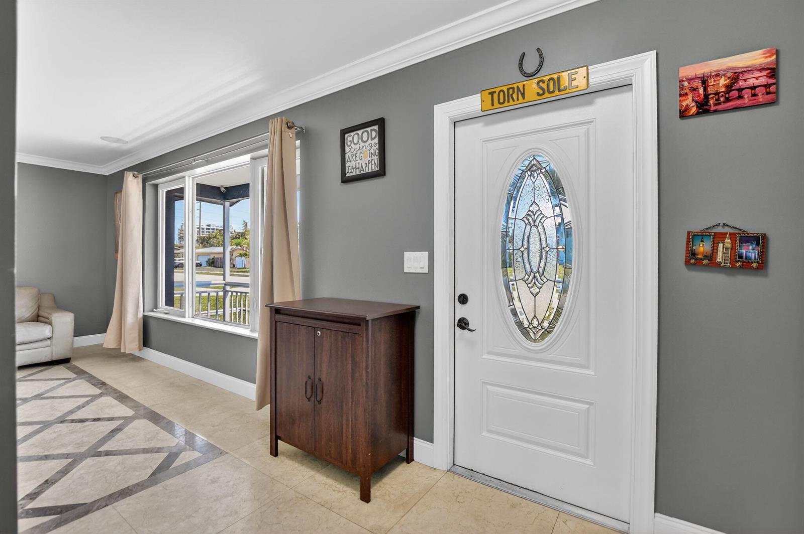 An entryway with gray walls, tile flooring, a white front door, and a wooden cabinet — 257 SW 5th Street, Boca Raton FL 33432, BOCA RATON, FL