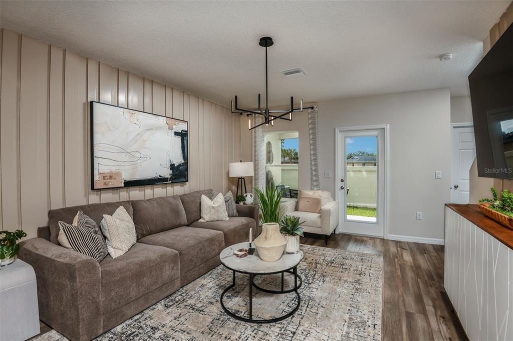 A living room features a brown sectional sofa, a marble coffee table, and vertical wall paneling — 4246 HILLOCK BOULEVARD, HAINES CITY, FL