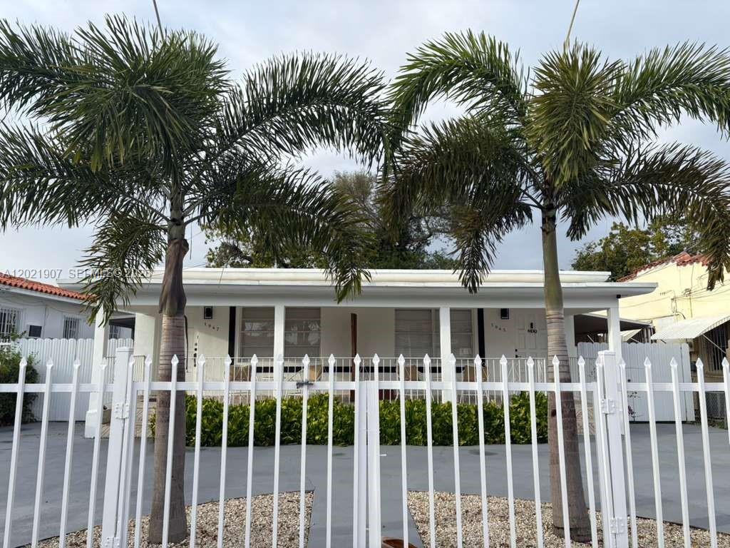 A white single-story house with a fenced front yard and two palm trees — 1947 NW 33rd St # 1, Miami FL 33142, MIAMI, FL