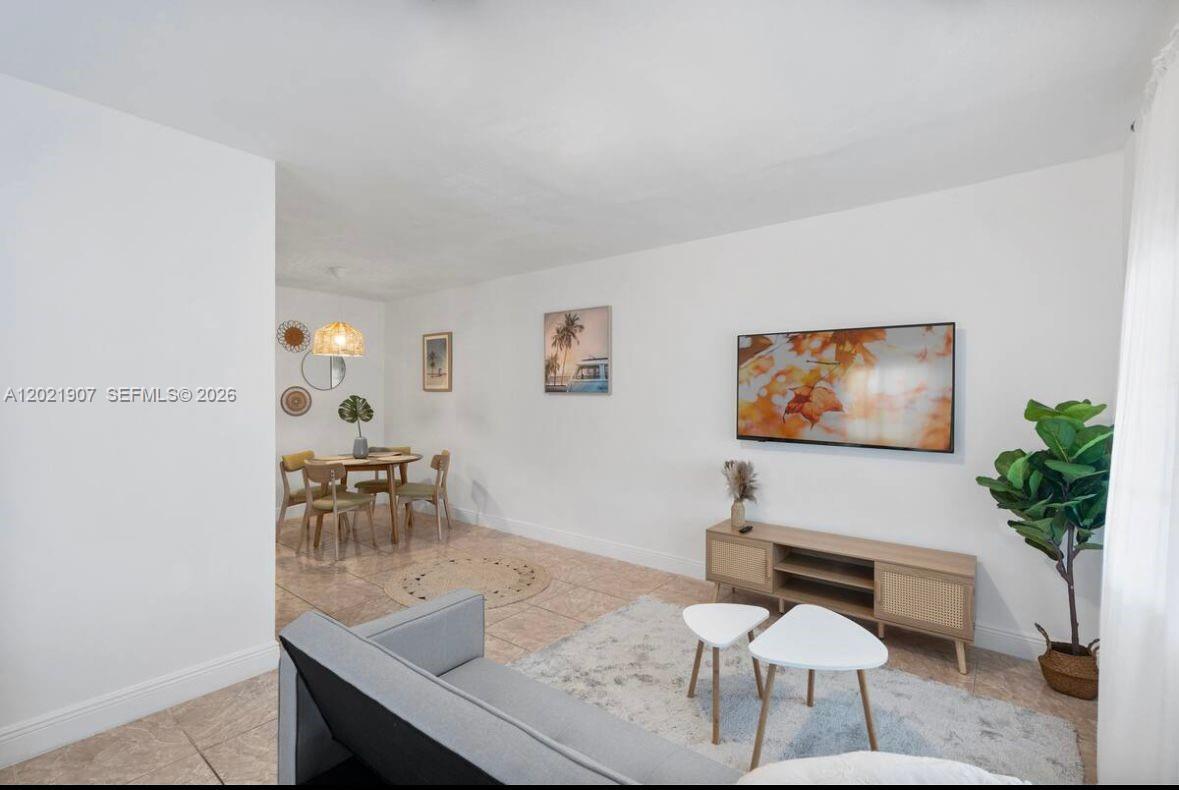 A living room and dining area with tile floors, white walls, and modern furniture — 1947 NW 33rd St # 1, Miami FL 33142, MIAMI, FL