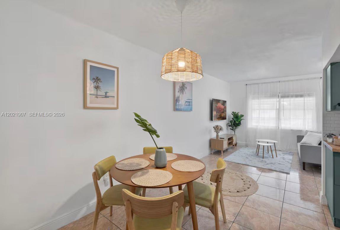 A dining area with a round wooden table sits adjacent to a living room — 1947 NW 33rd St # 1, Miami FL 33142, MIAMI, FL