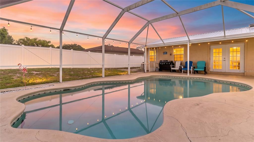 A swimming pool with a screened enclosure sits on a patio behind a residential home — 1480 EDISON TERRACE, DELTONA, FL