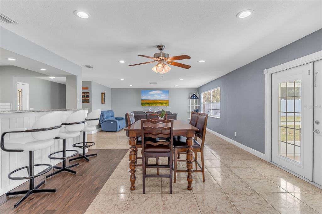 An open-concept dining and living area features tile flooring, a wooden table, and bar seating — 1480 EDISON TERRACE, DELTONA, FL