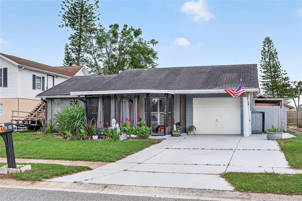 A single-story house with a screened front porch, a one-car garage, and a concrete driveway — 7644 HUMBOLDT AVENUE, NEW PORT RICHEY, FL
