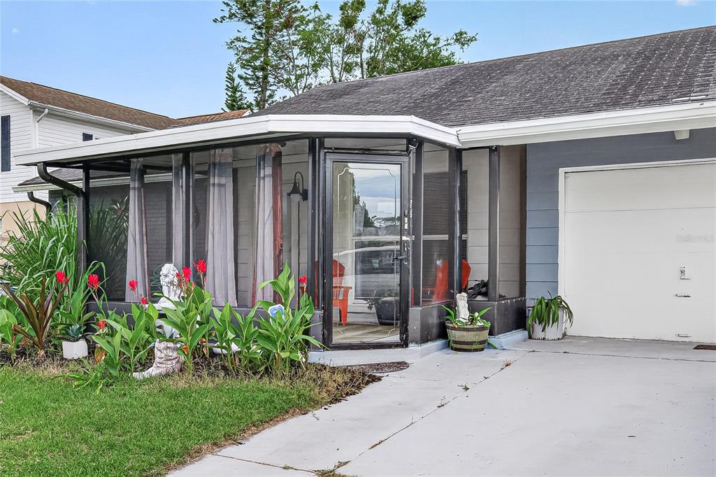 The exterior of a house features a screened-in front porch and an attached garage — 7644 HUMBOLDT AVENUE, NEW PORT RICHEY, FL