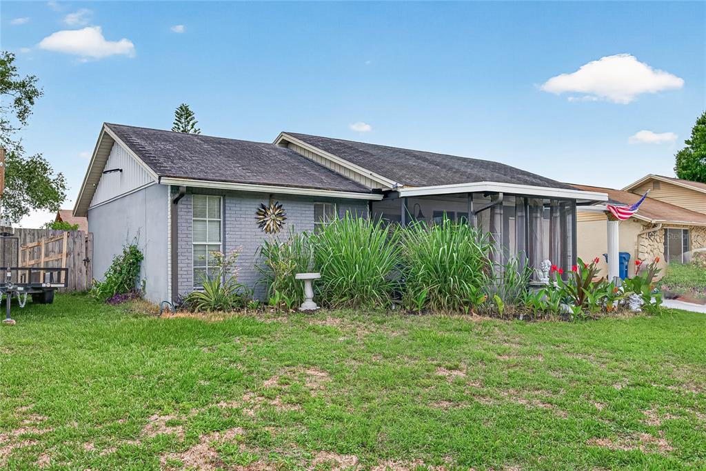 A single-story house with a grey brick exterior, a screened-in porch, and a grassy yard — 7644 HUMBOLDT AVENUE, NEW PORT RICHEY, FL