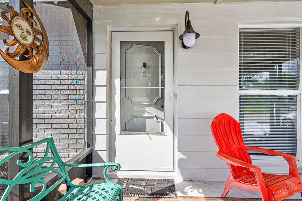 A front porch features a white door, a red Adirondack chair, and a green bench — 7644 HUMBOLDT AVENUE, NEW PORT RICHEY, FL