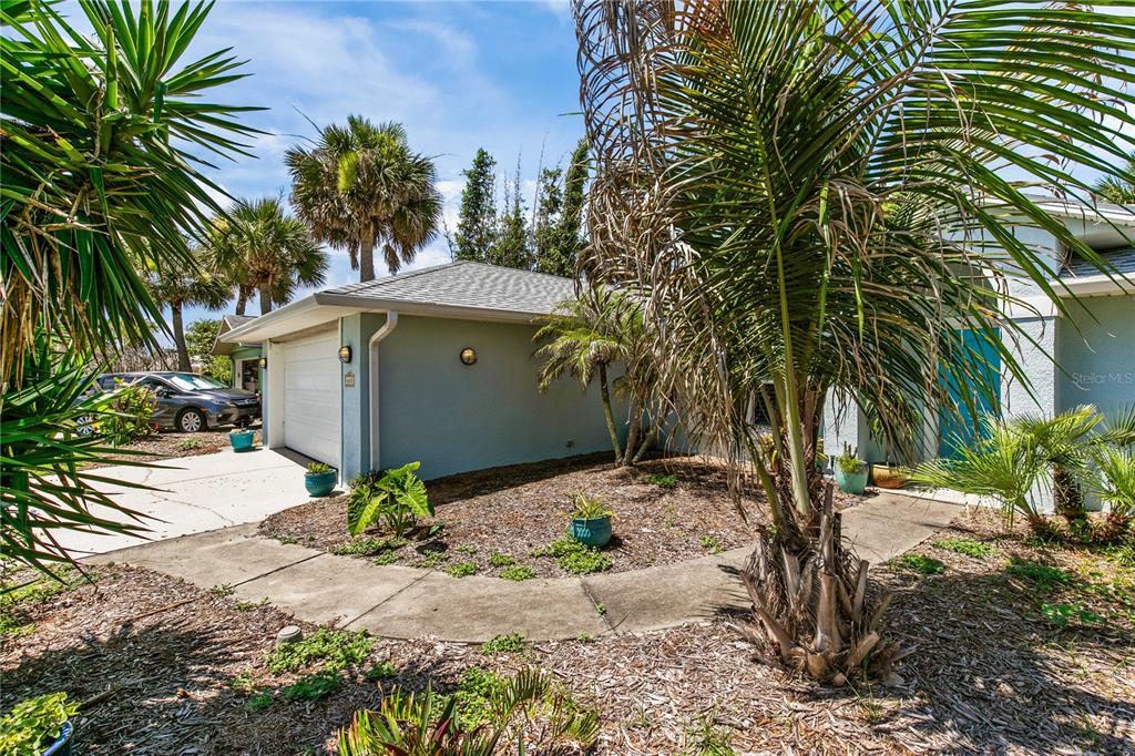A light blue house exterior features a garage, a curved walkway, and several palm trees — 4610 DORIS DRIVE, NEW SMYRNA BEACH, FL