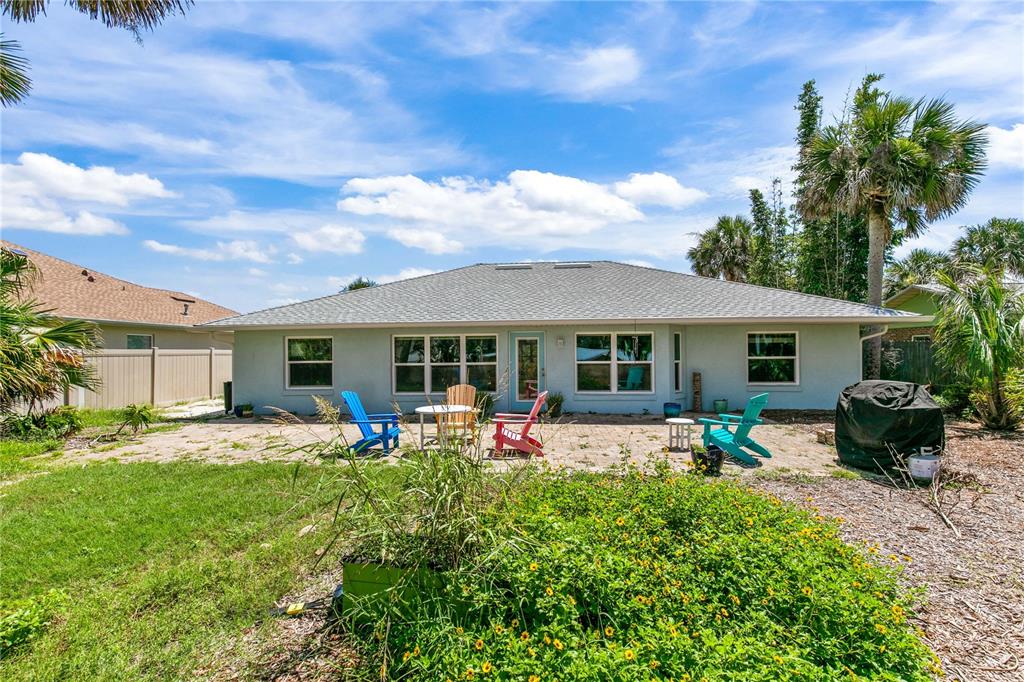 The exterior of a light blue house features a patio with chairs and a backyard — 4610 DORIS DRIVE, NEW SMYRNA BEACH, FL