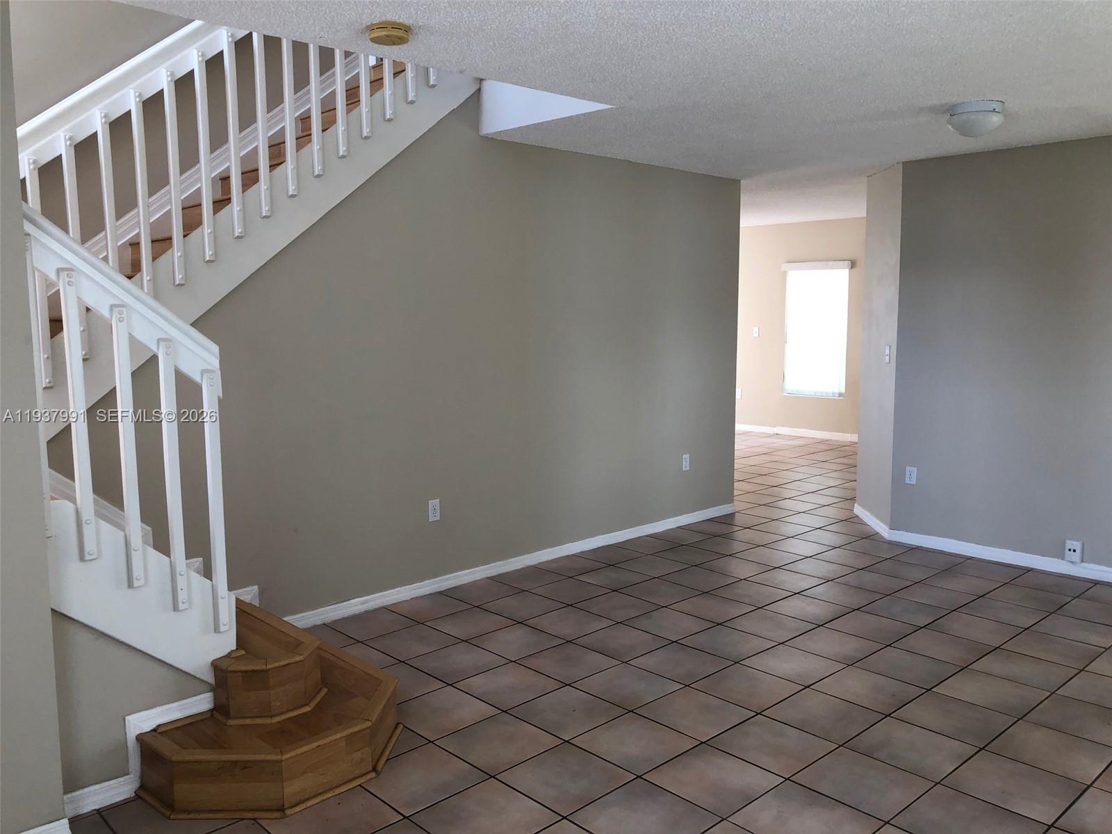 An interior view shows a staircase with wooden steps and white railings above tiled floors — 11274 SW 64 LN, Miami FL 33173, MIAMI, FL