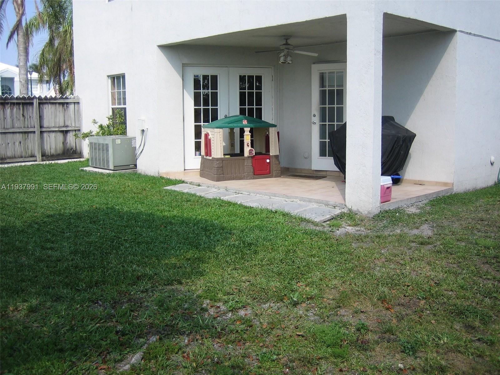 A white house exterior features a covered patio with a playhouse and a grill — 11274 SW 64 LN, Miami FL 33173, MIAMI, FL