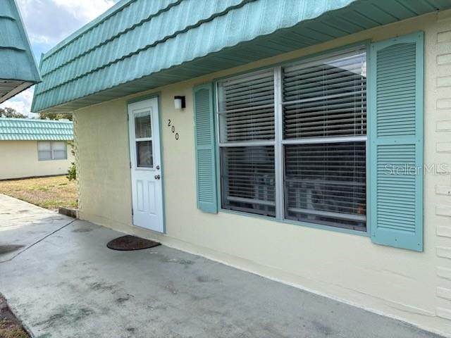 A single-story building with a light green roof and exterior walls features a central walkway — 101 CAMBRIDGE TRAIL UNIT 200, SUN CITY CENTER, FL